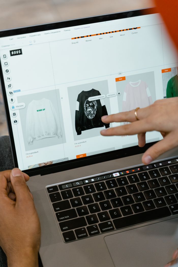 Gros plan sur des mains utilisant un site e-commerce sur l’écran d’un ordinateur portable en intérieur.